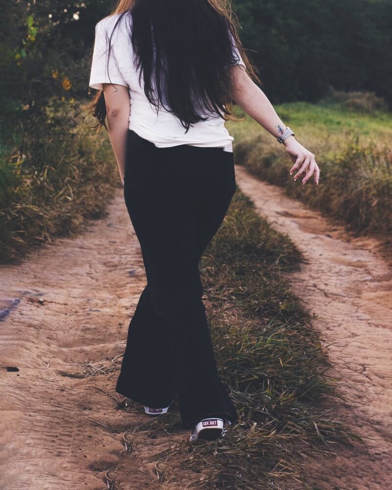 Девушка в черных брюках и белой футболке